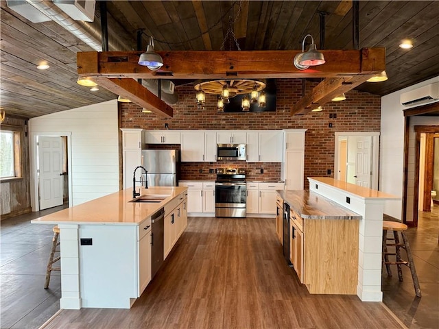 kitchen with a large island with sink, a sink, appliances with stainless steel finishes, and wooden ceiling