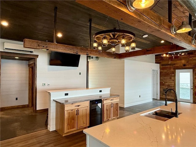 kitchen with baseboards, wooden walls, an AC wall unit, a chandelier, and a sink