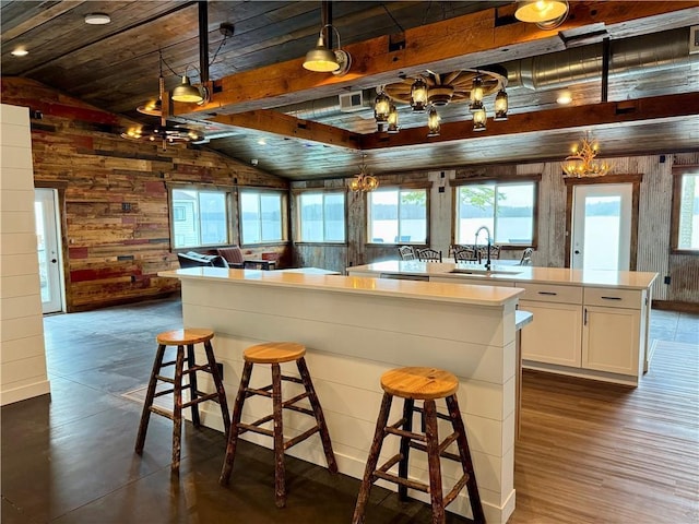 kitchen featuring vaulted ceiling, a sink, a notable chandelier, wooden walls, and a wealth of natural light