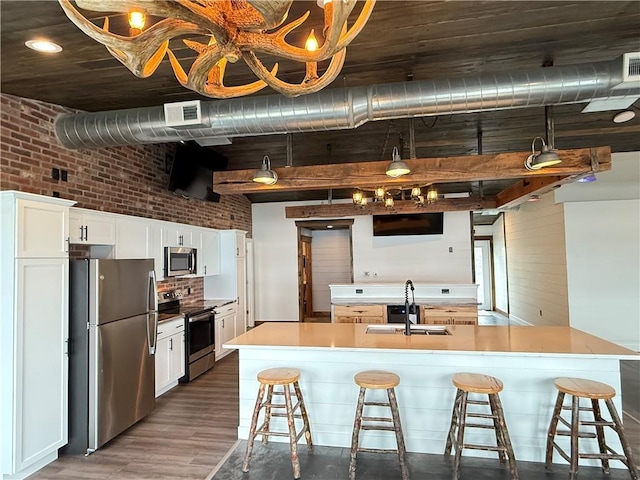 kitchen featuring a sink, appliances with stainless steel finishes, a breakfast bar area, and dark wood-style flooring
