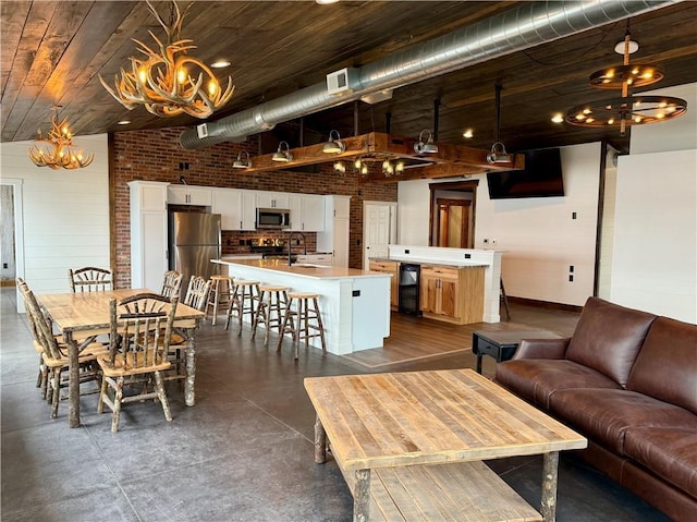 living room featuring a notable chandelier, finished concrete flooring, brick wall, baseboards, and visible vents