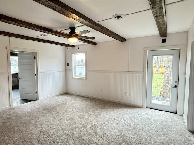 unfurnished room with ceiling fan, wainscoting, beam ceiling, carpet floors, and visible vents