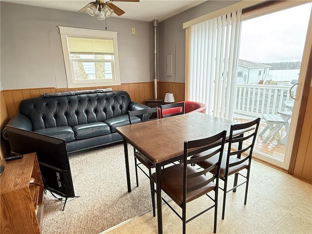 dining area featuring wooden walls, a wainscoted wall, and a ceiling fan