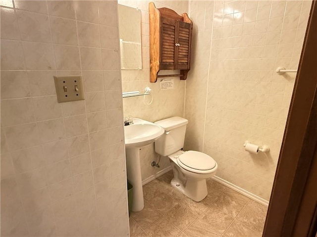 half bath featuring toilet and tile walls