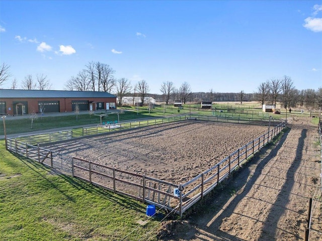 view of property's community with an enclosed riding area, a view of rural / pastoral area, and a garage