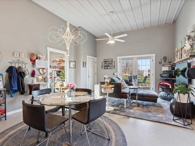 dining area with high vaulted ceiling, finished concrete floors, a ceiling fan, a chandelier, and french doors