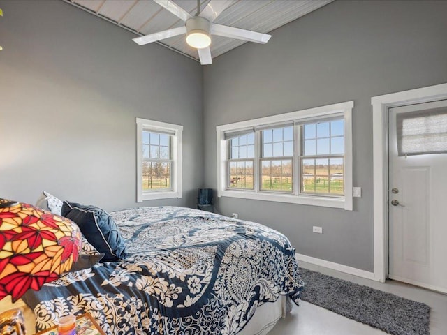 bedroom featuring baseboards, ceiling fan, and a high ceiling