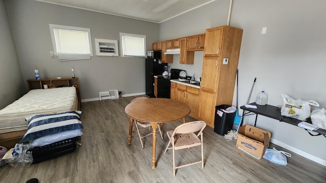 1110 Oakland Ave, Austin, MN 55912 - kitchen with black appliances, light wood-style flooring, under cabinet range hood, crown molding, and light countertops