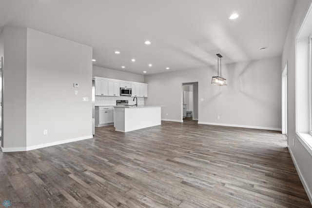 unfurnished living room with recessed lighting, baseboards, a sink, and dark wood-type flooring