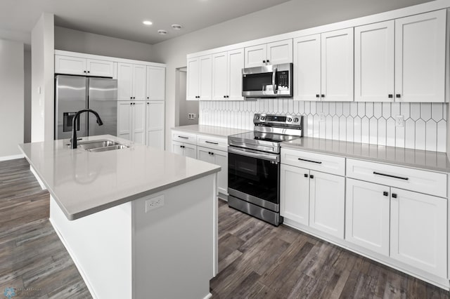 kitchen featuring appliances with stainless steel finishes, a sink, recessed lighting, white cabinetry, and tasteful backsplash