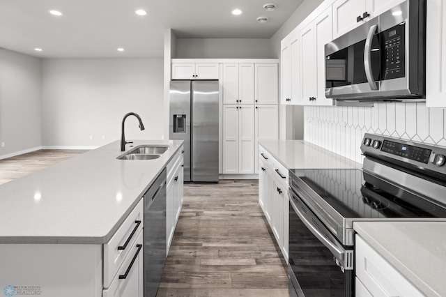 kitchen featuring white cabinets, appliances with stainless steel finishes, a sink, and light wood-style flooring