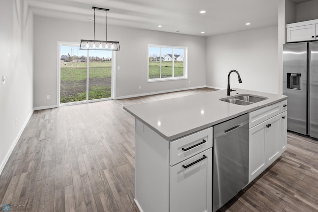 kitchen with wood finished floors, light countertops, white cabinetry, a sink, and appliances with stainless steel finishes