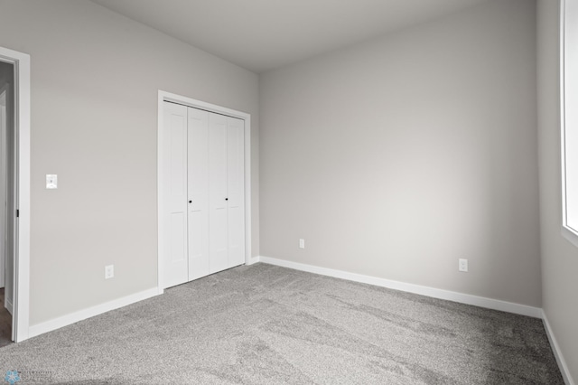 unfurnished bedroom featuring a closet, baseboards, and carpet flooring