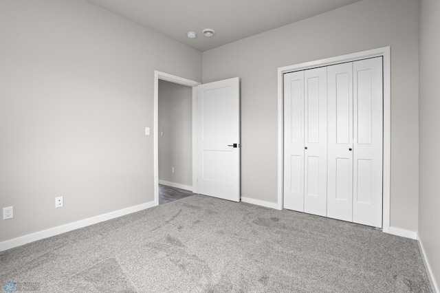 unfurnished bedroom featuring carpet floors, baseboards, and a closet
