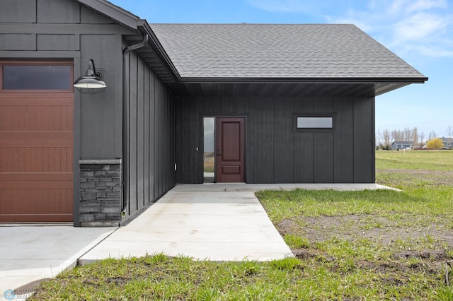 doorway to property with a lawn and a shingled roof