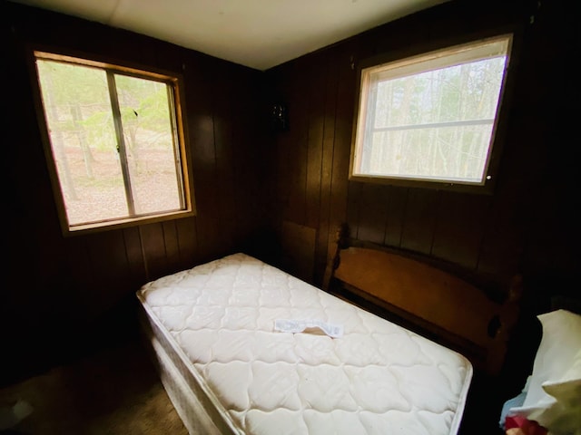 bedroom with multiple windows and wood walls