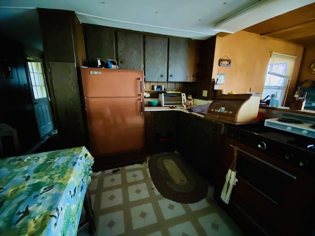kitchen featuring a toaster, tile patterned floors, and freestanding refrigerator