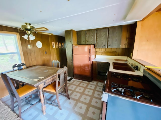 9199 County Road Y, Wascott, WI 54838 - kitchen with a sink, light floors, gas range oven, freestanding refrigerator, and wooden walls