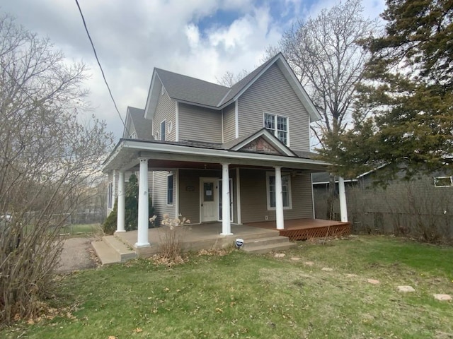 country-style home featuring a porch, a shingled roof, and a front lawn