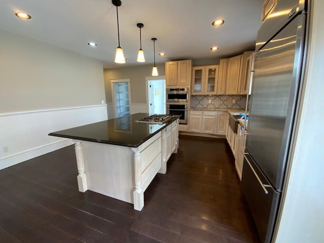 kitchen featuring wainscoting, a kitchen island, glass insert cabinets, backsplash, and stainless steel appliances