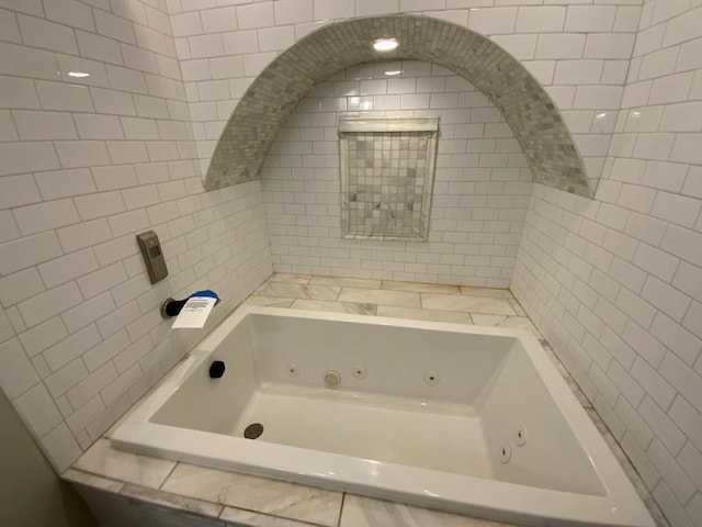 full bath with a whirlpool tub and tile walls