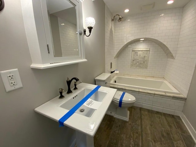 full bath with a sink, toilet, recessed lighting, wood finished floors, and tiled shower / bath combo