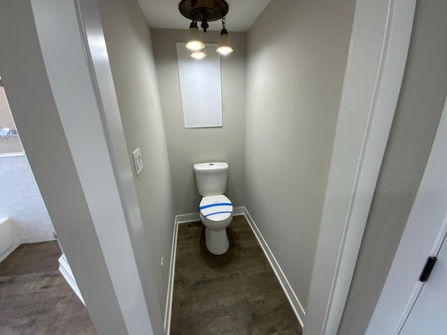 bathroom featuring toilet, baseboards, a washtub, and wood finished floors