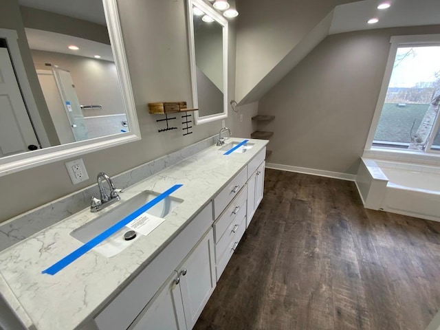 full bath featuring a sink, double vanity, recessed lighting, and wood finished floors
