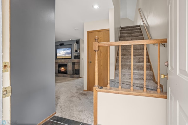 staircase with carpet, a lit fireplace, and recessed lighting