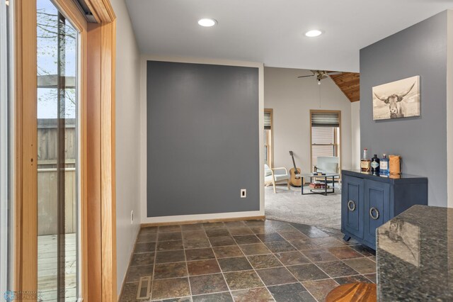 hallway featuring recessed lighting, stone tile flooring, lofted ceiling, and baseboards