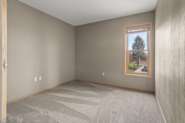 carpeted empty room featuring baseboards