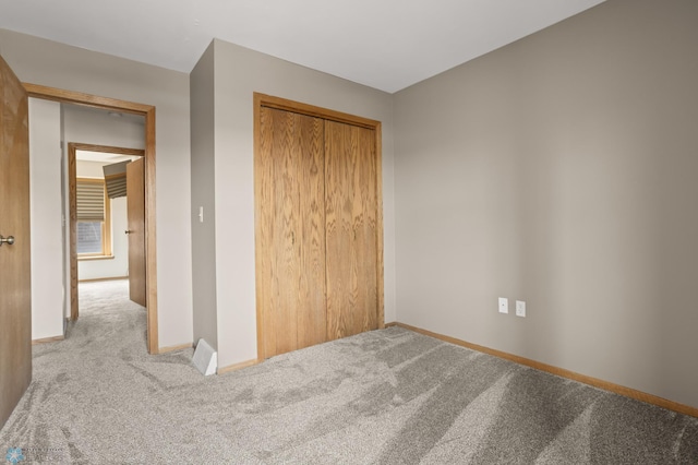 unfurnished bedroom with carpet floors, baseboards, and a closet