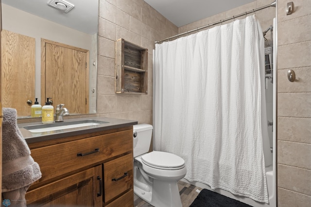 bathroom with tile walls, toilet, vanity, and shower / bathtub combination with curtain