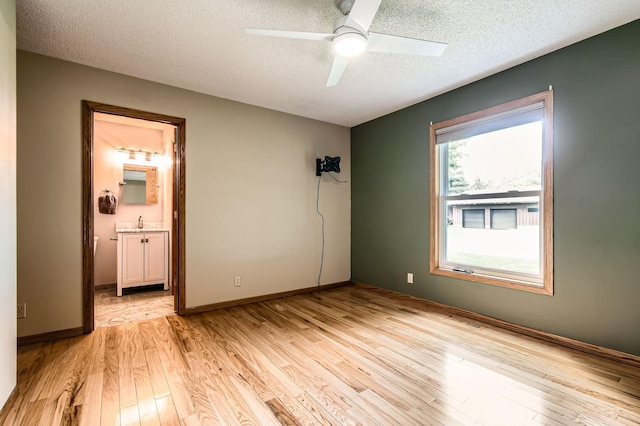 1877 Quasar Ave S, Lake Saint Croix Beach, MN 55043 - unfurnished bedroom featuring light wood-type flooring, a textured ceiling, connected bathroom, and a ceiling fan
