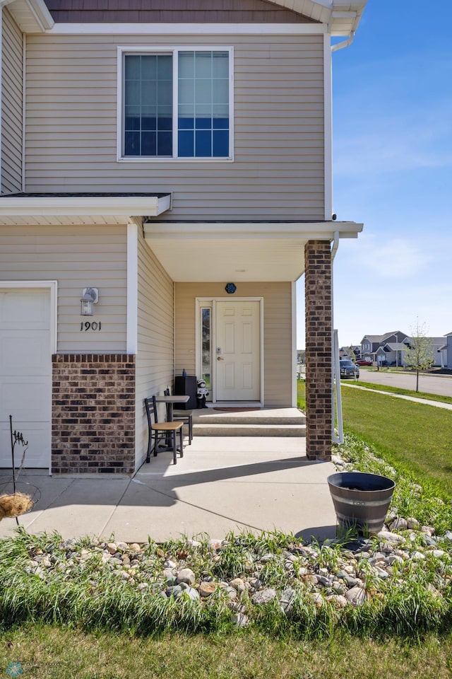 doorway to property with brick siding and a lawn