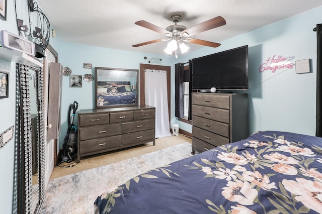 bedroom featuring ceiling fan, a textured ceiling, and light colored carpet