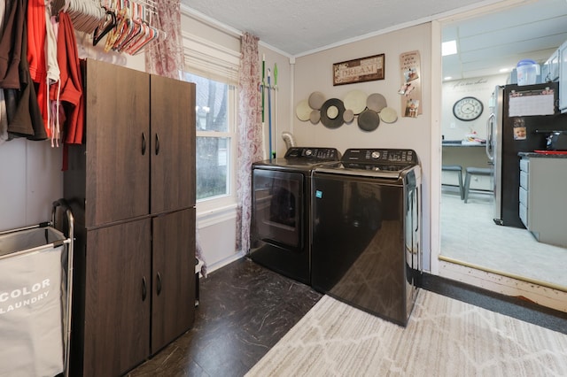 clothes washing area with crown molding, cabinet space, and washer and dryer