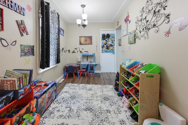 playroom featuring baseboards, a notable chandelier, and wood finished floors