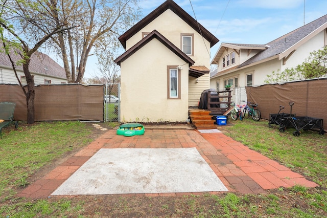 rear view of house featuring a patio, a gate, stucco siding, and fence