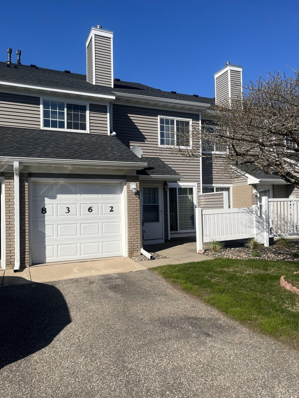 multi unit property featuring a chimney, driveway, and brick siding