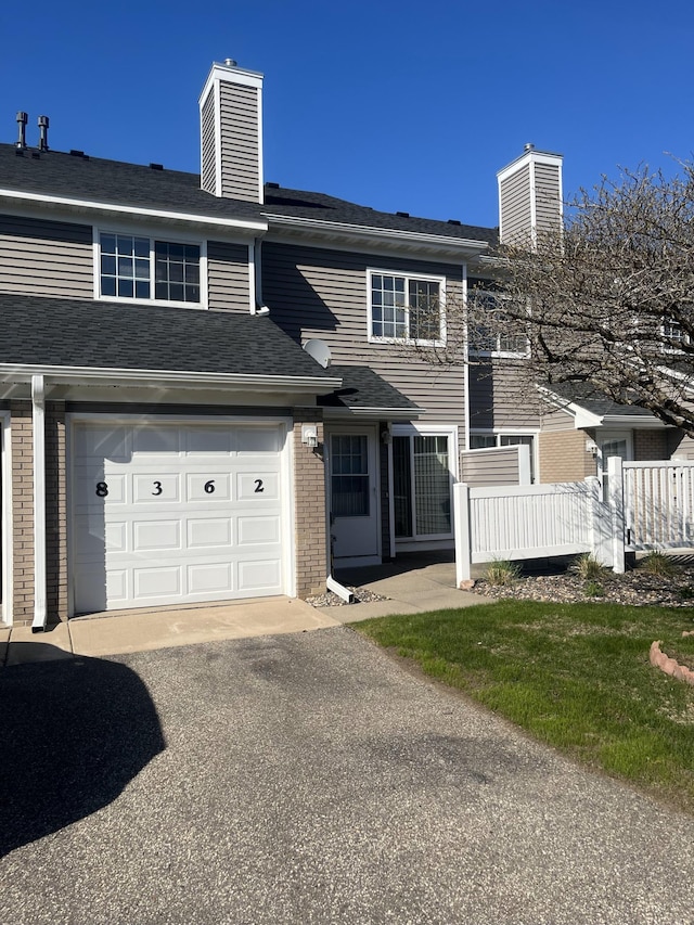 multi unit property featuring a chimney, driveway, and brick siding