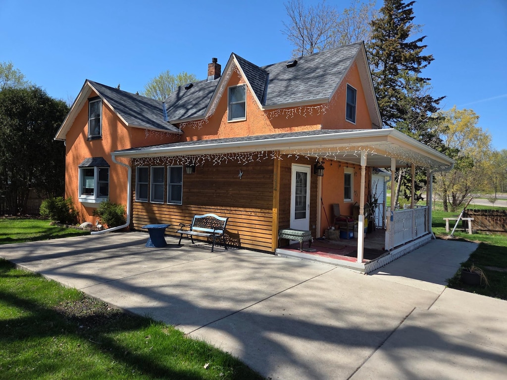 back of property with covered porch and a chimney