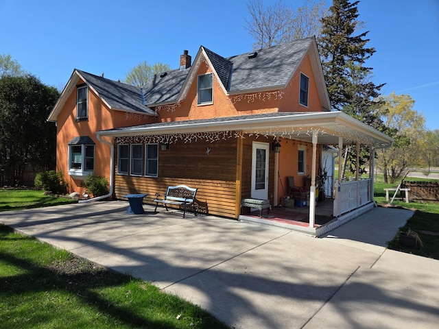 back of property with covered porch and a chimney