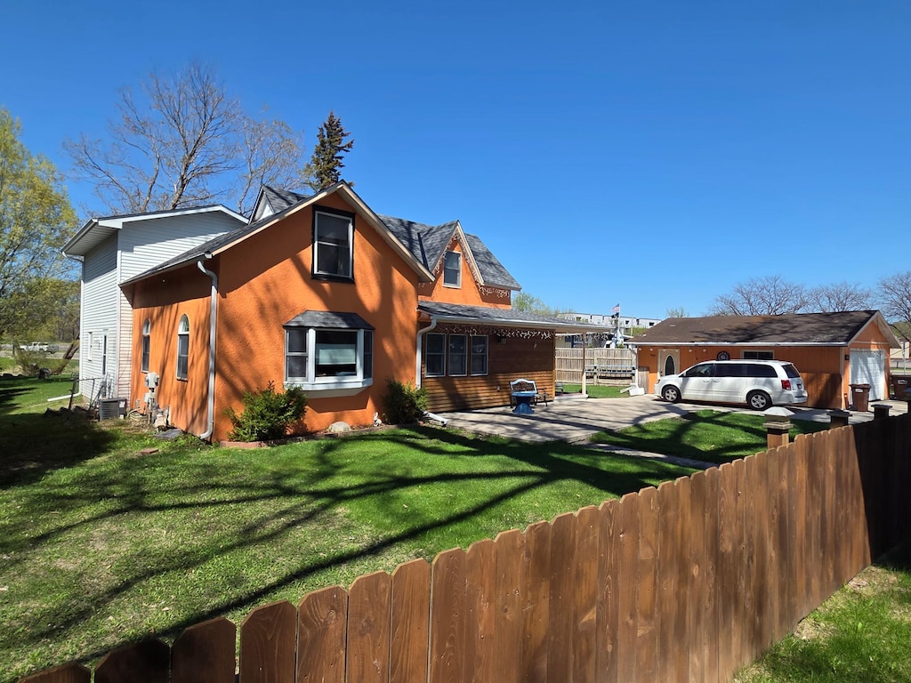 view of side of home with a lawn, cooling unit, and fence private yard