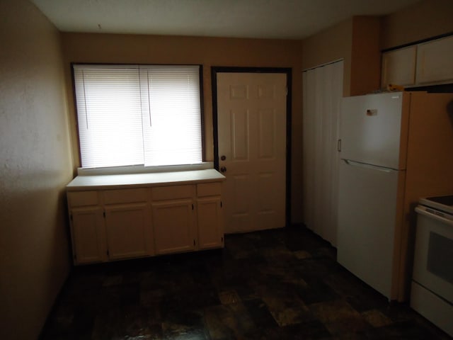 kitchen with light countertops, stone finish floor, white cabinets, and white appliances