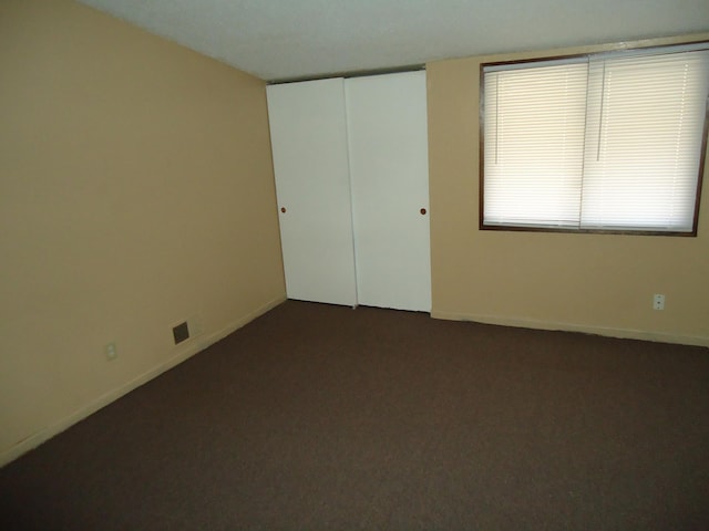 carpeted empty room featuring baseboards and visible vents