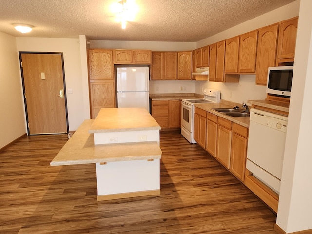 2155 6th Ln SE Unit 212, Cambridge, MN 55008 - kitchen with white appliances, under cabinet range hood, a textured ceiling, a center island, and dark wood-style flooring