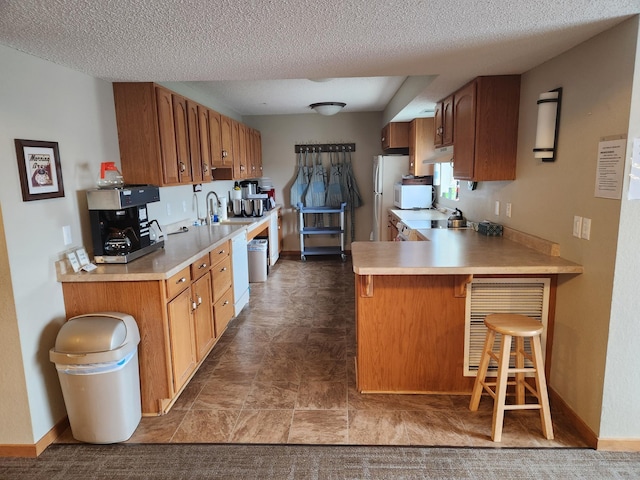 2155 6th Ln SE Unit 212, Cambridge, MN 55008 - kitchen featuring white appliances, light countertops, a peninsula, a kitchen breakfast bar, and a textured ceiling