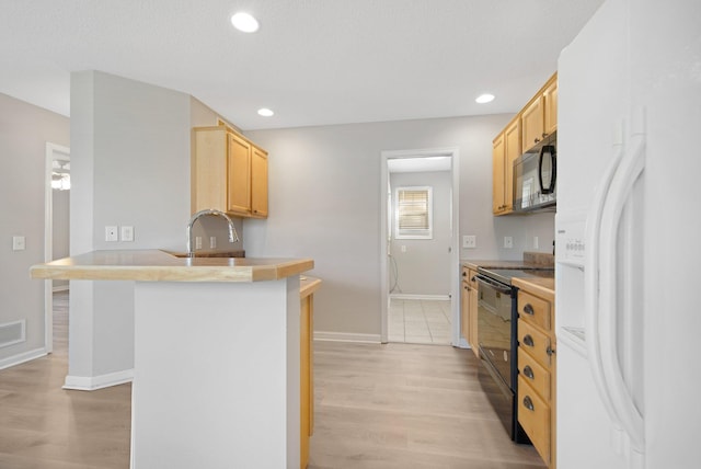 1501 Praha St SE, New Prague, MN 56071 - kitchen with a peninsula, a sink, light brown cabinets, baseboards, and black appliances