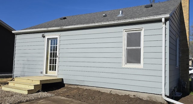 view of side of home with roof with shingles